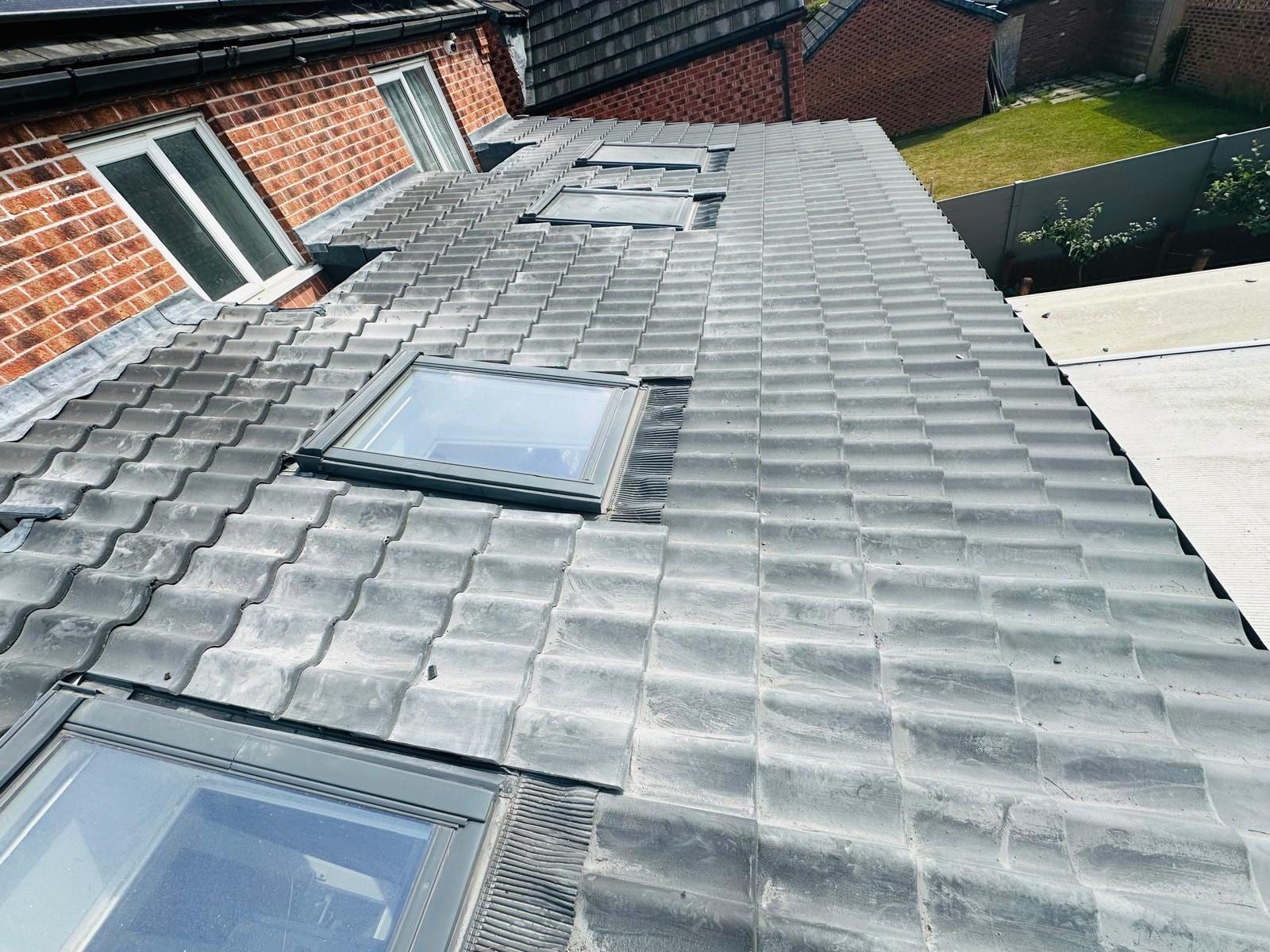A grey tiled roof with three new roof windows fitted in a row, seen from above